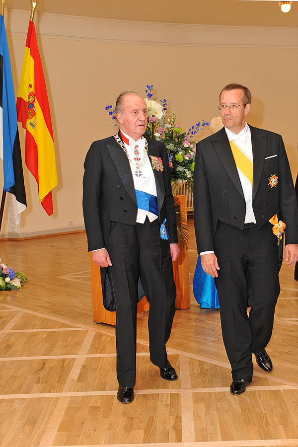 Kaks ametlikult riietatud meest riiklikul tseremoonial saalis, taustal lipud. 